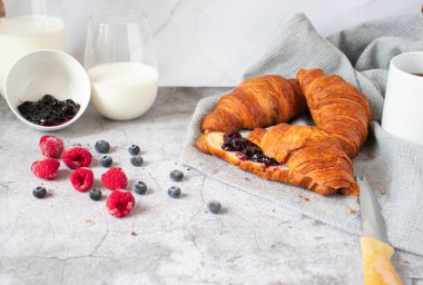 Breakfast with coffee and croissants, jam and berries. On a concrete background