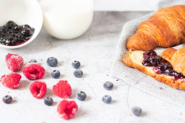 Breakfast with coffee and croissants, jam and berries. On a concrete background