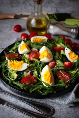 Salad with egg, arugula, tomatoes. On a concrete background. Vegetarian