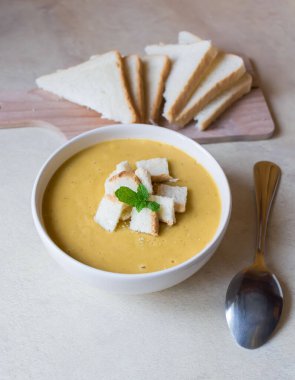 Pea soup in a white plate with crackers. lunch. Pieces of bread lie on a wooden board