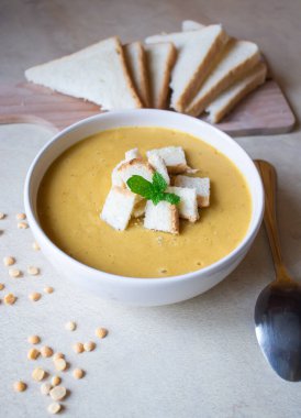 Pea soup in a white plate with crackers. lunch. Pieces of bread lie on a wooden board