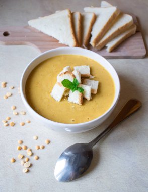 Pea soup in a white plate with crackers. lunch. Pieces of bread lie on a wooden board