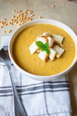 Pea soup in a white plate with crackers. lunch. Pieces of bread lie on a wooden board