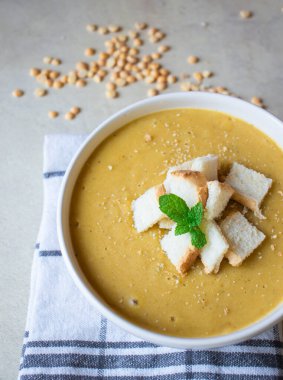 Pea soup in a white plate with crackers. lunch. Pieces of bread lie on a wooden board