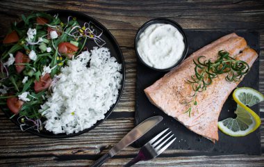 Cooked salmon with rice and salad. On a wooden background. dinner clipart