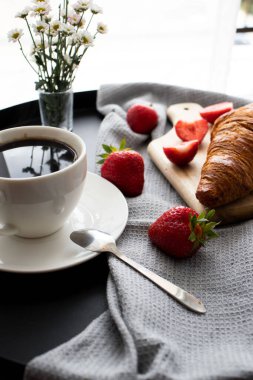 Kahveyle kahvaltı, kruvasan ve çilek masada. Günaydın.