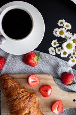 Kahveyle kahvaltı, kruvasan ve çilek masada. Günaydın.