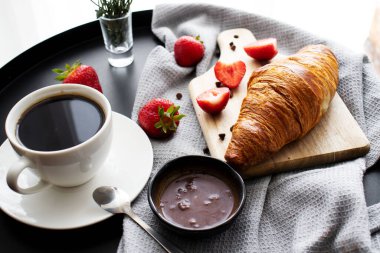 Kahveyle kahvaltı, kruvasan ve çilek masada. Günaydın.