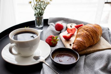 Kahveyle kahvaltı, kruvasan ve çilek masada. Günaydın.