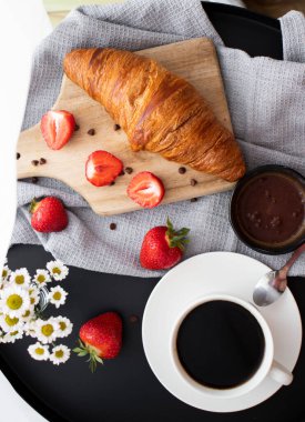 Kahveyle kahvaltı, kruvasan ve çilek masada. Günaydın.