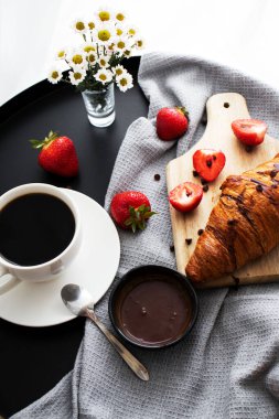 Kahveyle kahvaltı, kruvasan ve çilek masada. Günaydın.