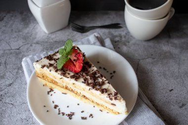 Kahve ve kek, çikolatalı ve siyah tabakta çilekli. Tatlı tatlı