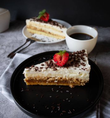 Kahve ve kek, çikolatalı ve siyah tabakta çilekli. Tatlı tatlı