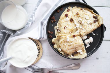 Peynirli krep ve tabakta kuru üzüm. Ahşap bir arka planda