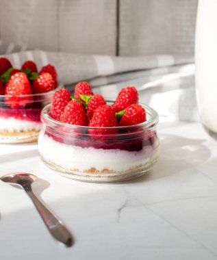 Cam kavanozdaki ahududulu cheesecake. beyaz arkaplanda.