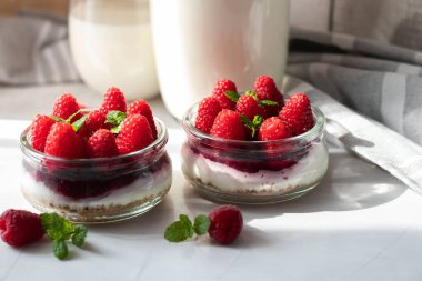 Cam kavanozdaki ahududulu cheesecake. beyaz arkaplanda.