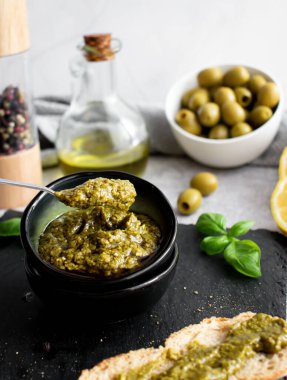 Beyaz arka planda taze malzemelerle bir kase pesto.