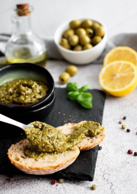 Pesto soslu kase ve tabak, ekmek ve zeytin.