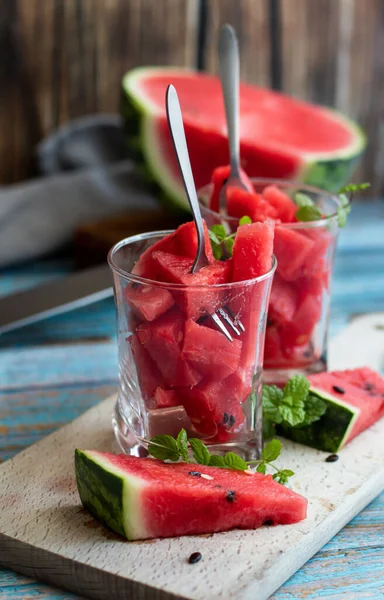 Watermelon slices in a glass on a wooden background. Slices of watermelon on a wooden board.