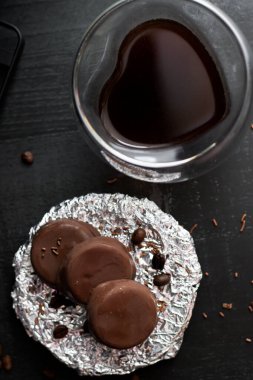 Çikolata kaplı cam bardakta kahve. Siyah bir arkaplanda.