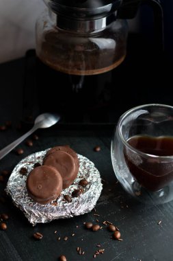 Çikolata kaplı cam bardakta kahve. Siyah bir arkaplanda.