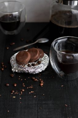 Çikolata kaplı cam bardakta kahve. Siyah bir arkaplanda.
