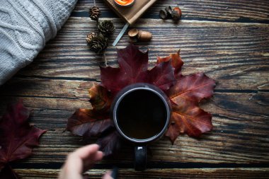 Bir fincan sıcak içecek, sonbahar yaprakları, kitaplar ve örgü kazaklar. ahşap bir arka planda