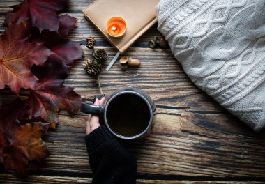 Bir fincan sıcak içecek, sonbahar yaprakları, kitaplar ve örgü kazaklar. ahşap bir arka planda