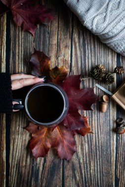 Bir fincan sıcak içecek, sonbahar yaprakları, kitaplar ve örgü kazaklar. ahşap bir arka planda