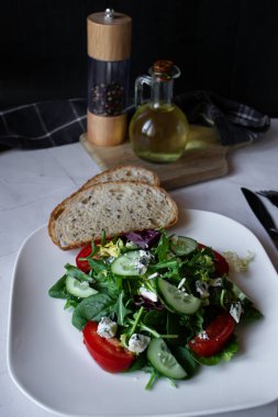 Sebzeli taze salata ve beyaz tabakta peynir.