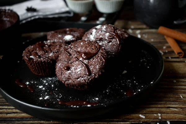 chocolate muffins with chocolate chips and a cup of coffee on a dark background.