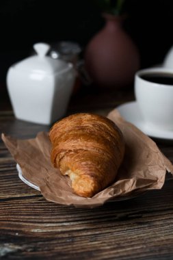 Sabah bir fincan kahve ve kruvasanla. Karanlık ahşap bir arka planda. Kahvaltı..