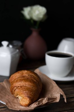 Sabah bir fincan kahve ve kruvasanla. Karanlık ahşap bir arka planda. Kahvaltı..