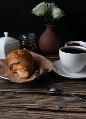 Sabah bir fincan kahve ve kruvasanla. Karanlık ahşap bir arka planda. Kahvaltı..
