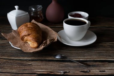 Sabah bir fincan kahve ve kruvasanla. Karanlık ahşap bir arka planda. Kahvaltı..