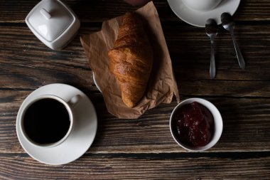 Sabah bir fincan kahve ve kruvasanla. Karanlık ahşap bir arka planda. Kahvaltı..