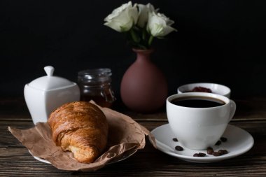 Sabah bir fincan kahve ve kruvasanla. Karanlık ahşap bir arka planda. Kahvaltı..