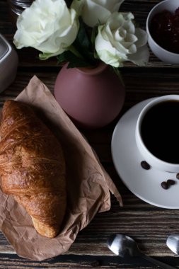 Sabah bir fincan kahve ve kruvasanla. Karanlık ahşap bir arka planda. Kahvaltı..