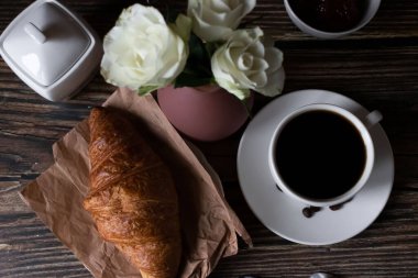 Sabah bir fincan kahve ve kruvasanla. Karanlık ahşap bir arka planda. Kahvaltı..