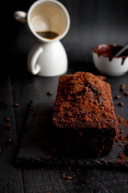 Çikolatalı kek, kakao tozu ve bir fincan kahve. Siyah arka plan. tatlı