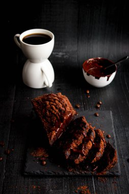 Çikolatalı kek, kakao tozu ve bir fincan kahve. Siyah arka plan. tatlı