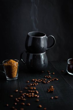 Kahve çekirdekleri, bir kaşık ve koyu arka planda bir fincan kahve. Güzel manzara. Günaydın, kahve. Siyah bir arka planda. Farklı kahve türleri.