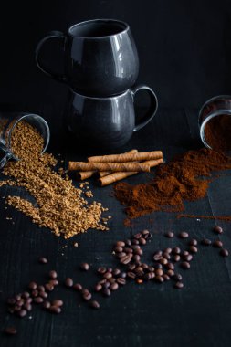 Kahve çekirdekleri, bir kaşık ve koyu arka planda bir fincan kahve. Güzel manzara. Günaydın, kahve. Siyah bir arka planda. Farklı kahve türleri.