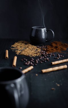 Kahve çekirdekleri, bir kaşık ve koyu arka planda bir fincan kahve. Güzel manzara. Günaydın, kahve. Siyah bir arka planda. Farklı kahve türleri.