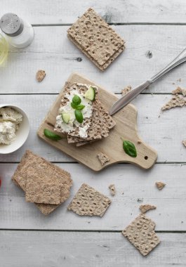 Peynirli, salatalık, keten tohumu ve ahşap zemin üzerinde naneli ev yapımı sağlıklı çıtır çıtır ekmek. Peynirli sağlıklı buğday ekmeği, ahşap zemin üzerinde salatalık. Kahvaltı