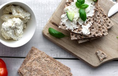 Peynirli, salatalık, keten tohumu ve ahşap zemin üzerinde naneli ev yapımı sağlıklı çıtır çıtır ekmek. Peynirli sağlıklı buğday ekmeği, ahşap zemin üzerinde salatalık. Kahvaltı