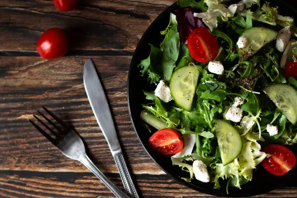 Taze salata, roka, vişneli domates ve peynir. Tahta bir arka planda. sağlıklı yiyecekler