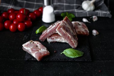 Bıçak, tuz, biber ve baharatla siyah arka planda çiğ domuz eti, pişirme konsepti. en üstteki görünüm.