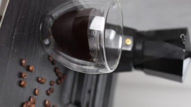 Siyah arka planda bir fincana koyu kahve dökülüyor..