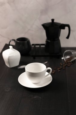 Kahve fincanı ve çay tabağı karanlık bir odada, ahşap bir masada.